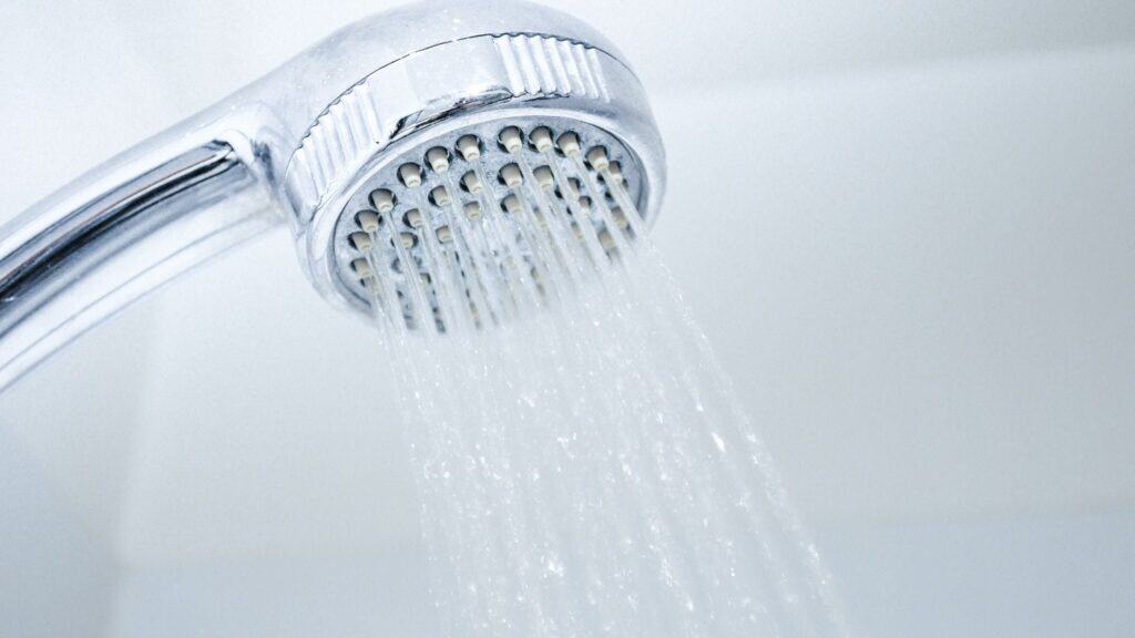 Close-up of a showerhead spraying water in a bathroom setting.