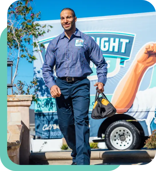 A man in business attire carries a small bag and walks outdoors in front of a branded truck with a logo and contact information.