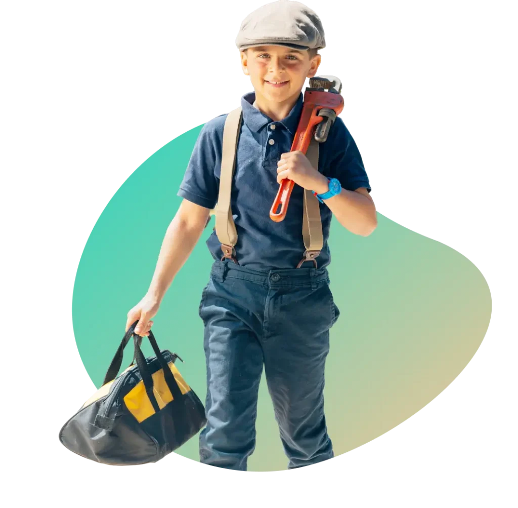 A boy wearing a cap, suspenders, and a navy shirt holds a large pipe wrench over his shoulder and carries a tool bag in his other hand.